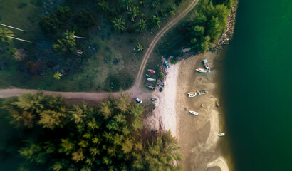 Aerial top view on sand beach, palm tree, ocean and boat.