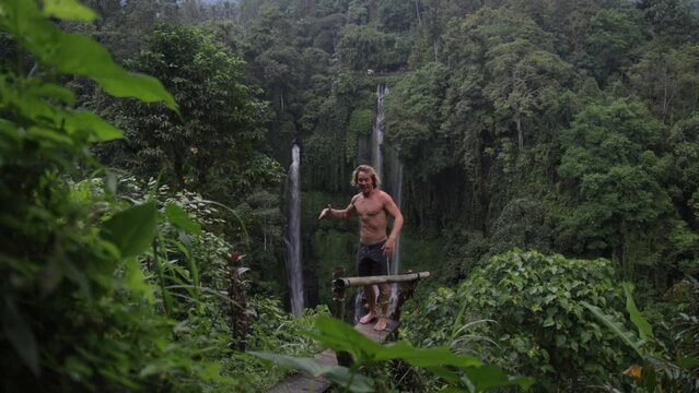 Slow motion of a handsome man with muscular body dancing at the Sekumpul waterfalls in the jungles of Bali Indonesia