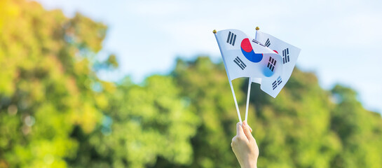 hand holding Korea flag on nature background. National Foundation, Gaecheonjeol, public Nation holiday, National Liberation Day of Korea and happy celebration concepts