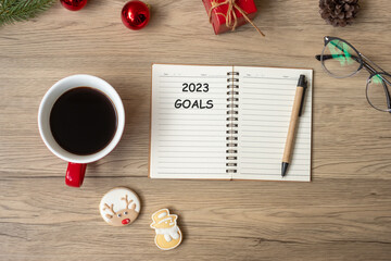 2023 GOAL with notebook, black coffee cup, Christmas cookies and pen on wood table. Xmas, Happy New Year, Resolution, To do list, Strategy and Plan concept