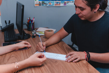 Travel agent closing a deal with a young man. Two people signing a sales contract. Two people at a wooden desk closing a deal. High quality photo