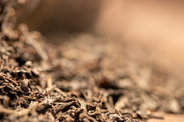 Large-leaf black tea in a glass and scattered on the table. Close-up of the surface texture
