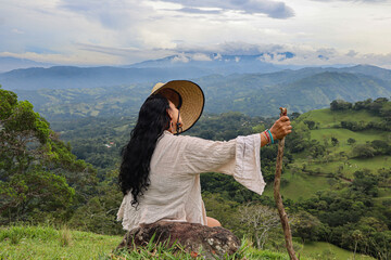 Woman sitting on top of a mountain taking her hat off