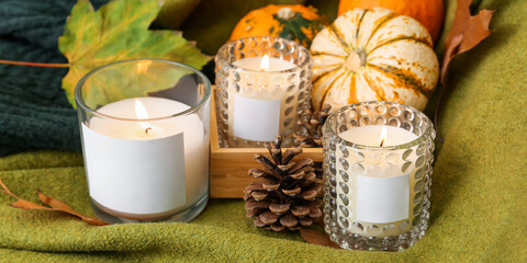Beautiful burning candles with autumn decor on sofa