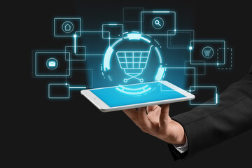 Hand of businessman with tablet computer on dark background. Online shopping concept