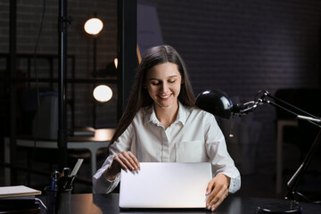 Smiling businesswoman working with laptop in office at night