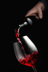 Pouring red wine in a glass goblet.