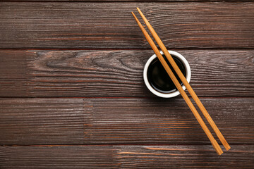 Bowl of soy sauce and chopsticks on dark wooden background