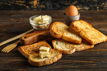 Slices of toasted bread and butter on wooden background