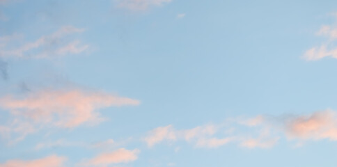 Blue sky background with pale pink clouds at sunset