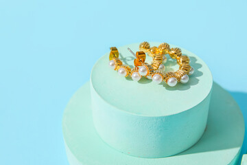Showcase pedestal with pearl earrings on blue background, closeup