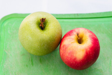 High quality photography. Close up of a couple of apples of different colors in a top view. One red apple and one green.