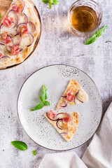 Slices French tarte flammkuchen with bacon, cream cheese and onion on a plate. Top and vertical view