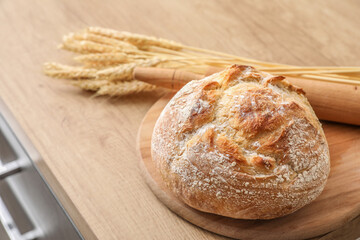 Naklejka premium Cutting board with fresh bread on table in kitchen, closeup