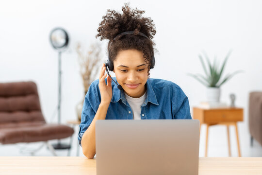 Beautiful woman call center worker in headphones is working at modern office. Portrait of African American female support employee, communicating with customer