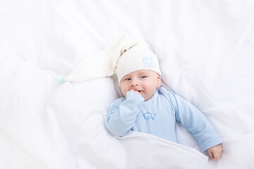 baby boy on the bed under the blanket in the hood, healthy sleep of the newborn