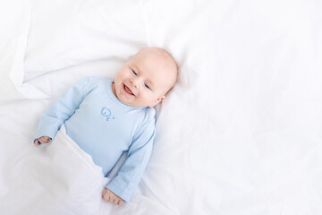 laughing baby boy on the bed under the blanket, healthy sleep baby