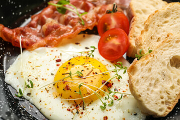 Tasty fried egg, bacon, spices and bread, closeup