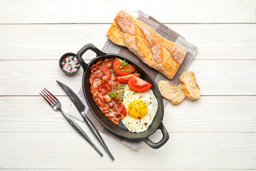 Fototapeta na wymiar Frying pan with tasty fried egg, bacon, tomatoes and bread on light wooden background