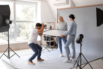 Male photographer and his assistant working with mature woman in studio