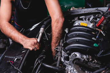 High quality photography. An unrecognizable mechanic reaching into the engine of a car he is repairing. Mechanic checking engine of a car to find the problem.