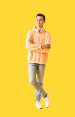 Fototapeta na wymiar Teenage boy with headphones on yellow background