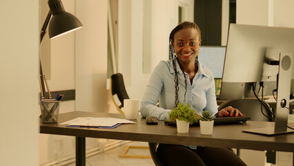 Portrait of businesswoman using computer at company desk, working on research data and paperwork. Analyzing online information to do report and take notes, sending executive email.