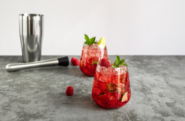 Raspberry daiquiri, alcoholic cocktail with raspberry, white rum, lime juice, and crushed ice in glasses, with steel bar tools. Summer refreshing drink.