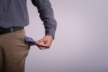 Poor businessman hand holding and showing his empty pocket money with gray background copy space...