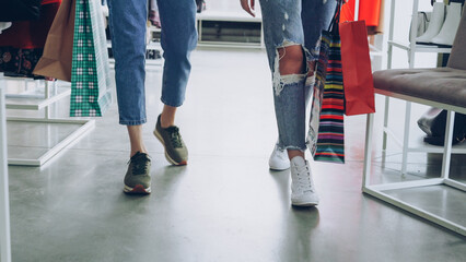 women's legs walking slowly through luxurious shop. Women are wearing jeans and trainers and...