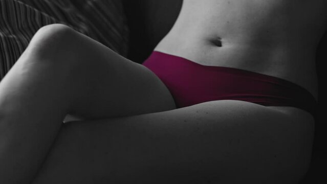 Partly colored desaturated -  tilt down of beautiful woman sitting on couch wearing red lingerie