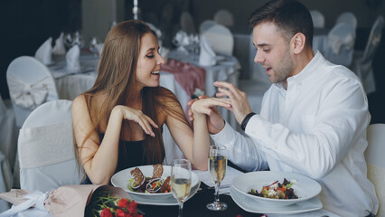 Attractive young woman is saying yes to marriage proposal. Romantic relationship and restaurant date concept.