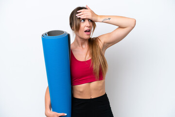 Young sport woman going to yoga classes while holding a mat isolated on white background doing surprise gesture while looking to the side