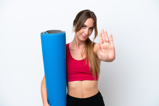 Young Sport Woman Going To Yoga Classes While Holding A Mat Isolated On White Background Making Stop Gesture