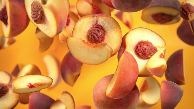 Super Slow Motion Shot of Peach Cuts Flying Towards Camera on Orange Background at 1000 fps.