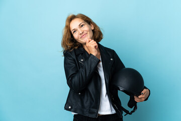 Georgian girl holding a motorcycle helmet isolated on blue background and looking up