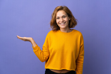 Young Georgian woman isolated on purple background holding copyspace imaginary on the palm to...