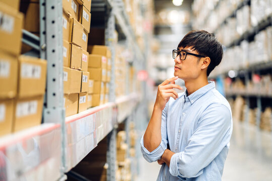Portrait of smiling asian engineer man order details checking goods and supplies on shelves with goods background in warehouse.logistic and business export.