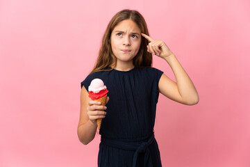 Child with a cornet ice cream over isolated pink background having doubts and thinking