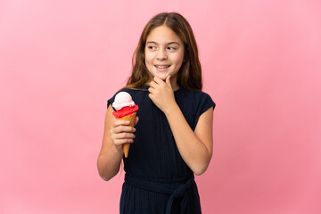 Child with a cornet ice cream over isolated pink background looking to the side and smiling
