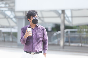 Fototapeta premium Sweating asian business man wearing face mask using mobile phone during office hours as part of Business New Normal