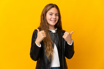 Child over isolated yellow background with thumbs up gesture and smiling