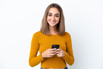 Young caucasian woman isolated on white background looking at the camera and smiling while using the mobile