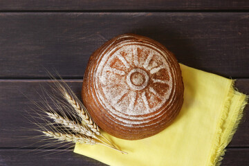 Freshly baked bread and ears of rye lie on a wooden board. Harvest. Top view. Selective focus