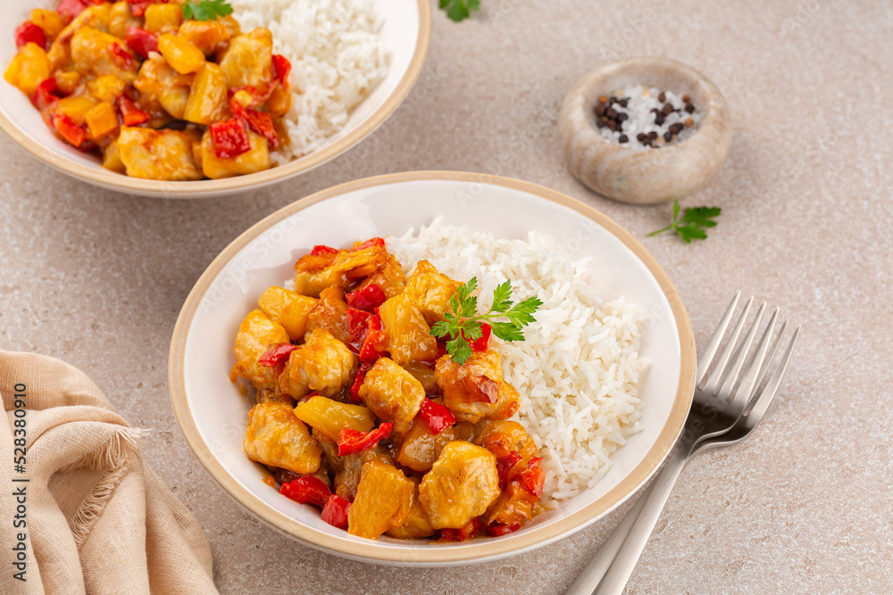 Poster Turkey curry cooked with bell peppers and pineapple.  Basmati rice. Two portions on a beige table surface.