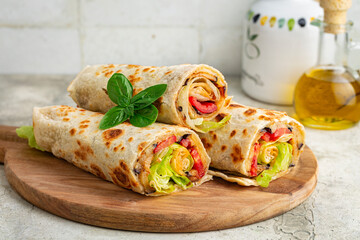 Wraps with a soft flatbread rolled around a filling with vegetables and cheese, tomato, fried...
