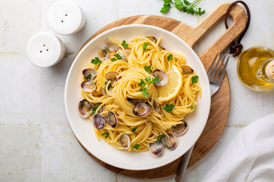 Italian pasta spaghetti with clams and lemon or Spaghetti alle vongole verace, cooked with oil, white wine, garlic, parsley. Top view.
