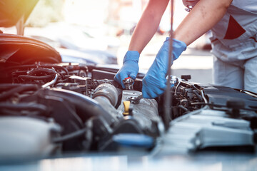 female car service technician inspects and repairs a customer's car at a car service center.