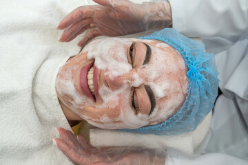 female cosmetologist in protective gloves works with a client in her salon.