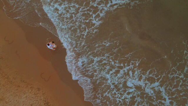 Aerial of a romantic couple slow dancing at the Kilyos beach while the foamy waves hit the sand